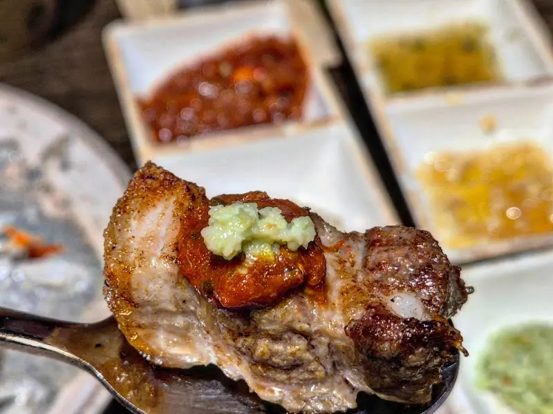 잘 익은 삼겹살 위에 와사비와 갈치속젓을 올려 한 입에 먹기 직전의 모습