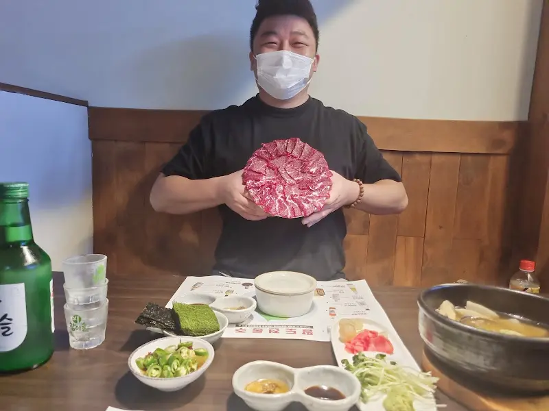 사장님이 뭉티기 접시를 들고 환하게 웃고 있는 모습