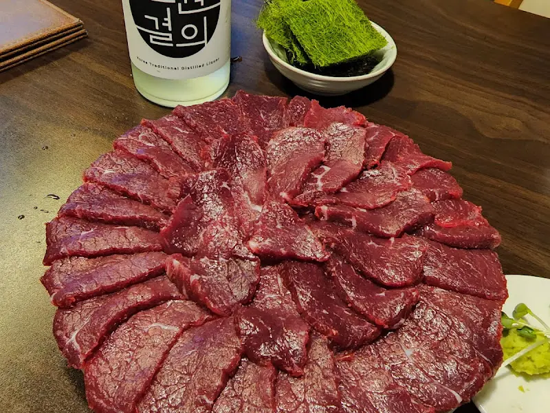 테이블 위에 놓인 뭉티기 접시와 술병