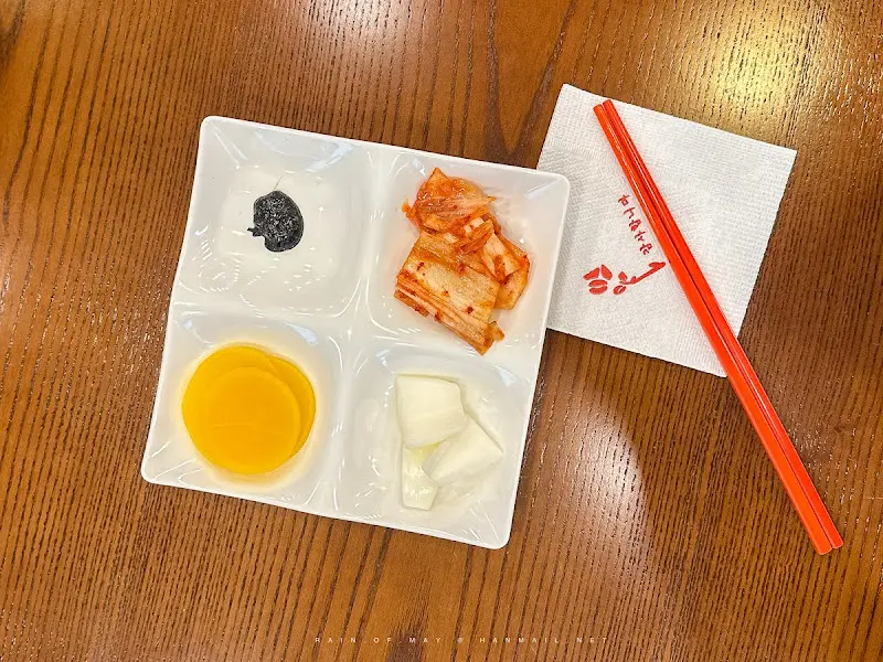 네 칸으로 나뉜 접시에 담긴 단무지, 양파, 김치, 춘장