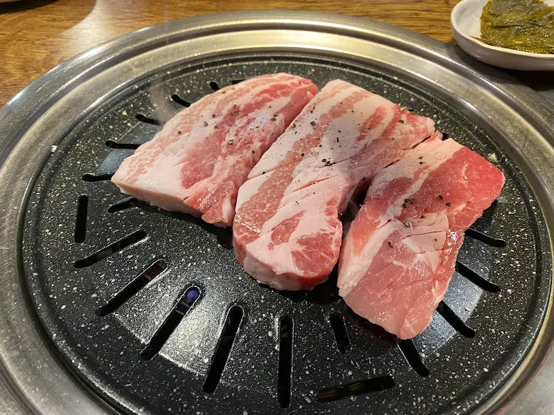 두툼한 숙성 삼겹살이 불판 위에 올려진 모습