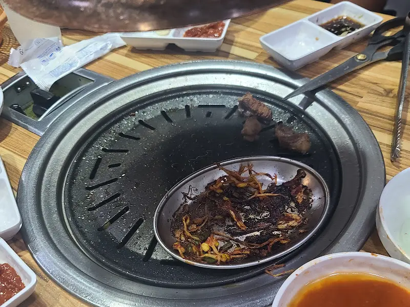 불판 위에 구워지고 있는 고기와 주변 반찬들