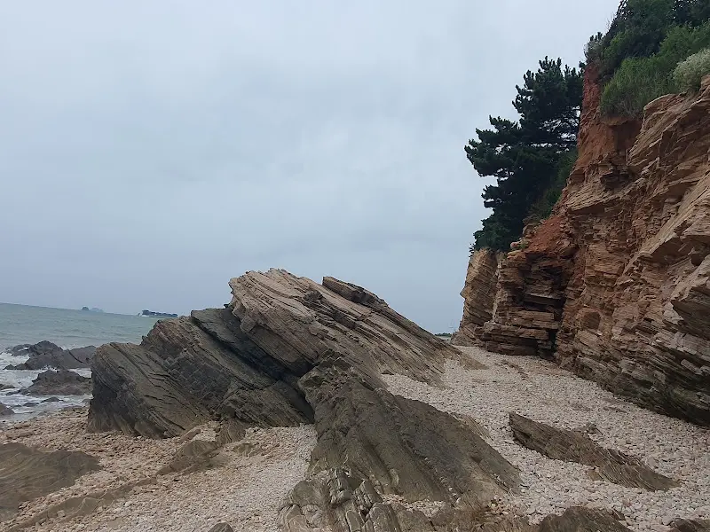 해변 뒤편으로 보이는 층층이 쌓인 듯한 절벽.