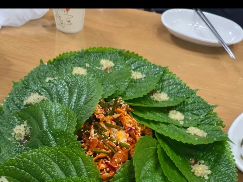 깻잎 위에 다진 마늘이 올려진 우럭회무침