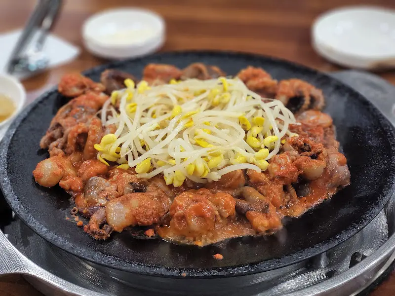 철판 위에 쭈꾸미와 콩나물이 함께 볶아져 있는 모습