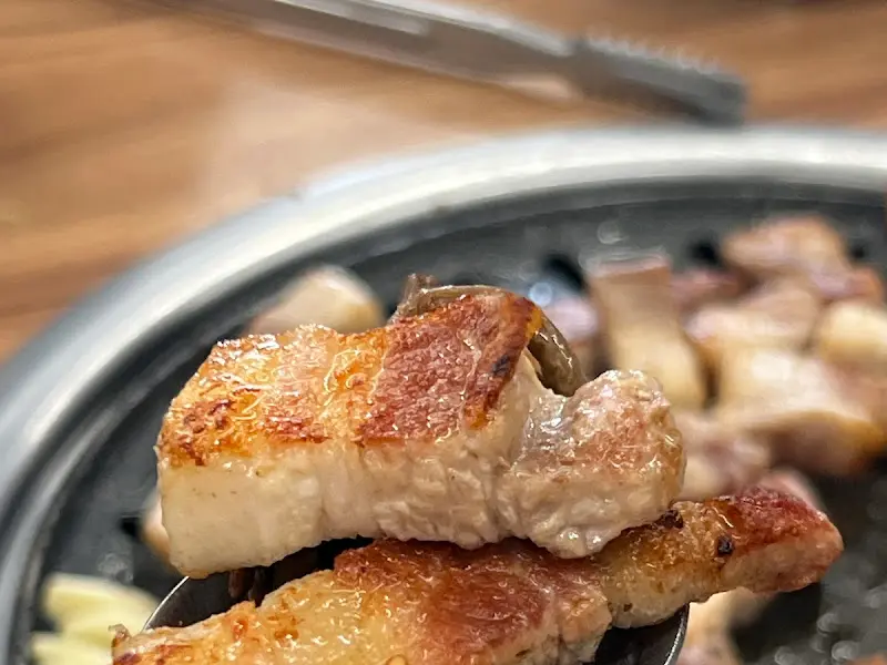 잘 익은 돼지고기를 집게로 들어올리는 모습