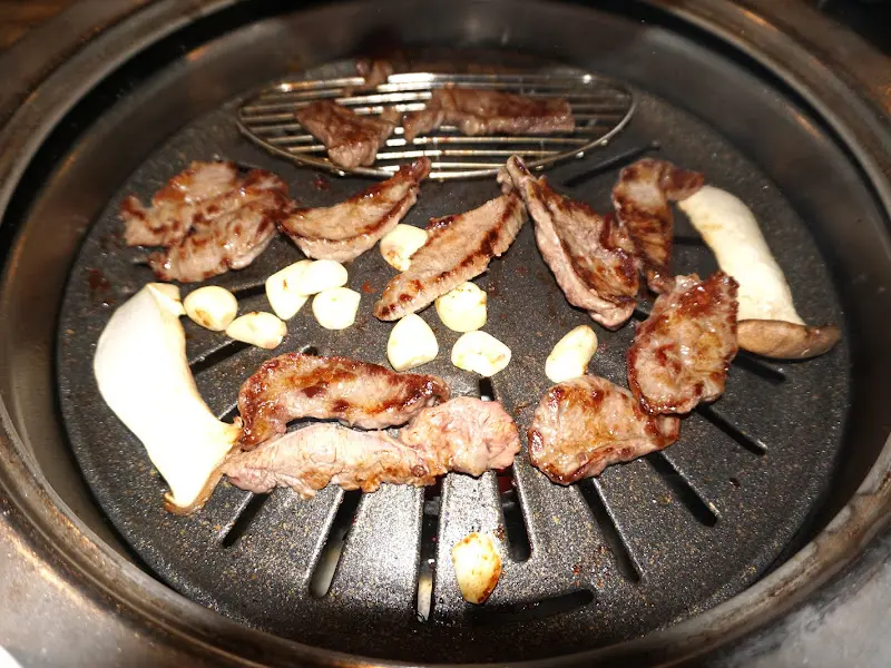 숯불 위에서 노릇노릇 익어가는 고기와 마늘