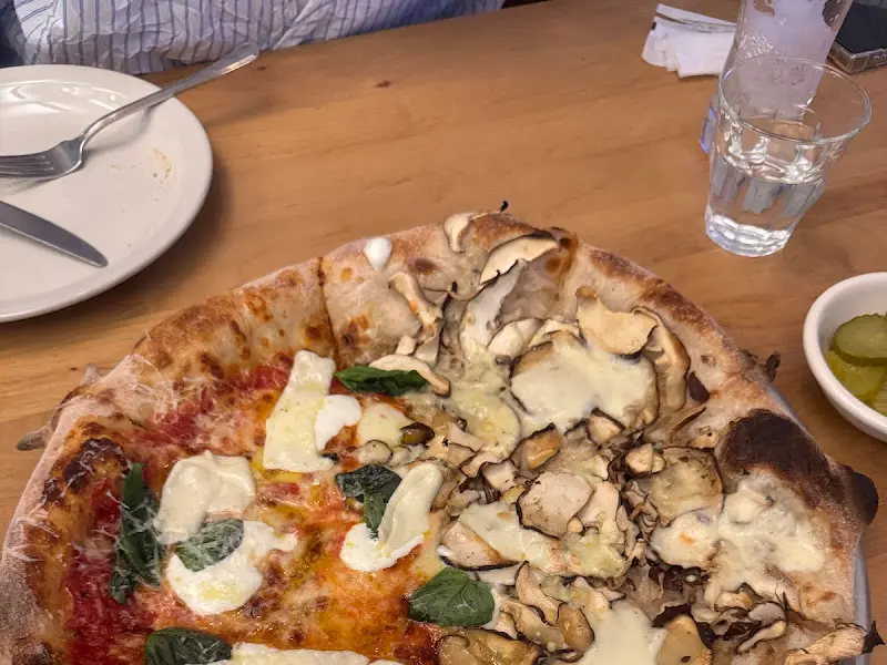 테이블 위에 놓인 피자와 물컵, 개인 접시의 모습