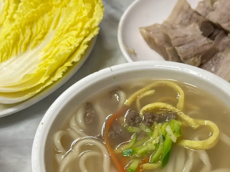 칼국수와 보쌈이 함께 담긴 테이블 사진