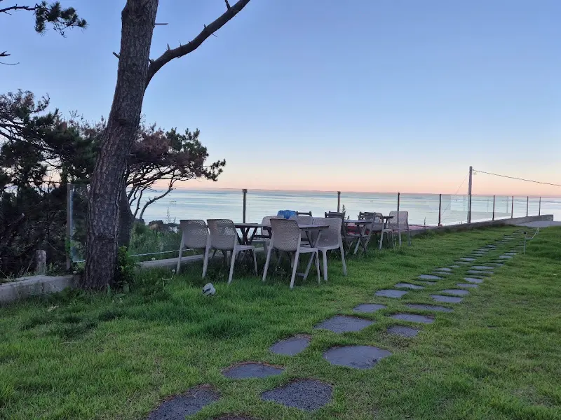 카페 외부 테이블 좌석. 파라솔 아래 앉아 바다를 감상하며 여유를 즐길 수 있다.