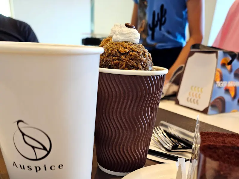 블랙 크럼블 라떼와 티라미수 케이크. 음료 위에는 크럼블이 가득 올려져 있고, 티라미수 케이크는 촉촉해 보인다.