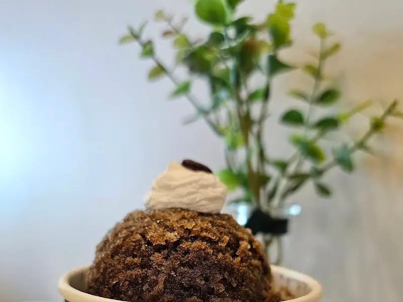 블랙 크럼블 라떼 클로즈업. 음료 위에 올려진 크럼블이 먹음직스럽다.