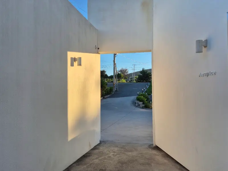 카페 입구. 흰색 벽으로 둘러싸여 있고, 독특한 조명이 설치되어 있다.