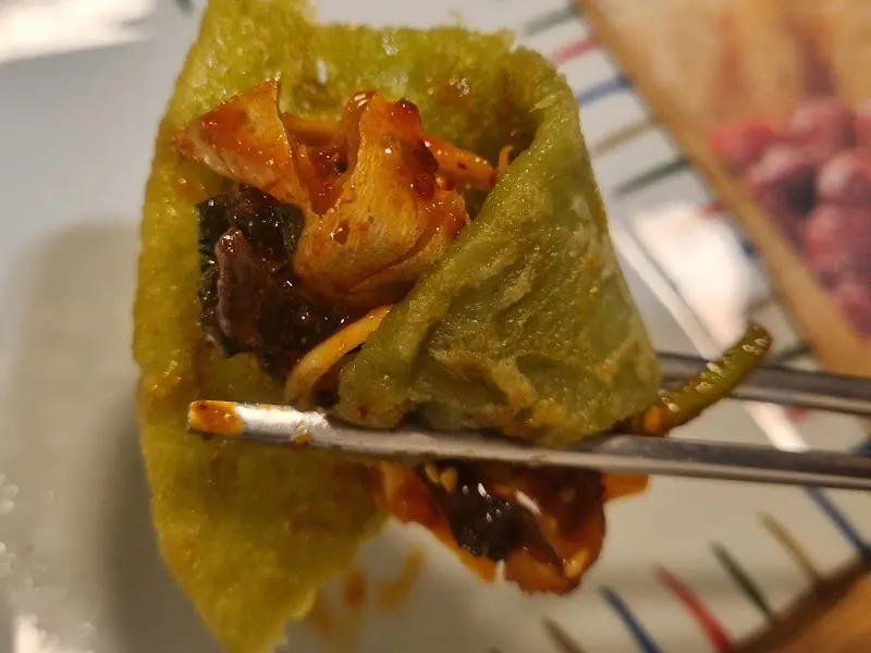 녹두전에 복껍질 무침을 싸서 먹는 모습