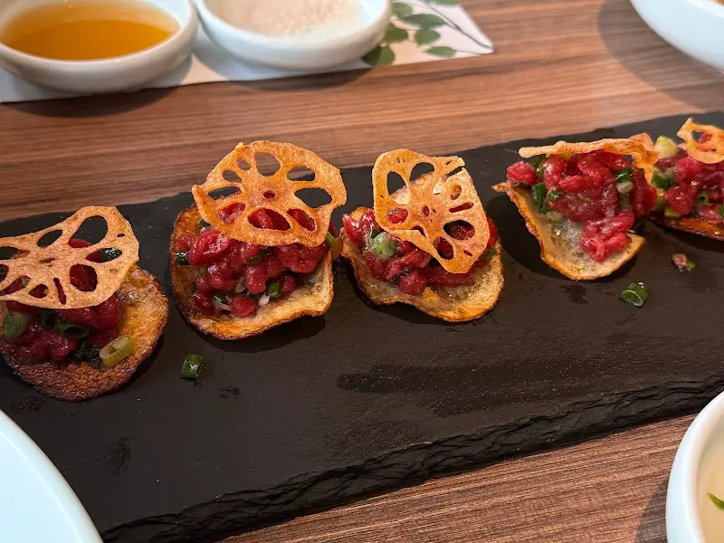 육회 위에 연근 튀김을 올린 메뉴