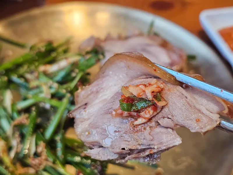 수육에 김치를 곁들여 먹는 모습