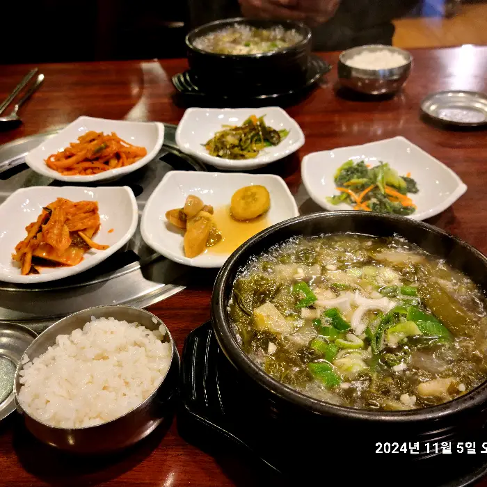 놋그릇에 담긴 국물 요리와 밥, 그리고 여러 반찬
