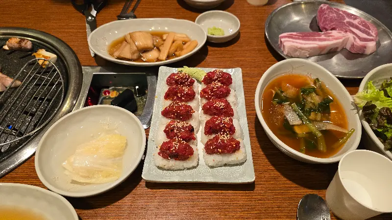 육회 초밥과 각종 밑반찬이 차려진 테이블