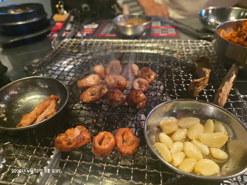 잘 구워진 막창, 마늘과 함께 숯불 위에 올려져 있는 모습