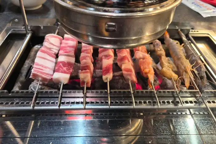 양꼬치, 소고기, 새우 꼬치가 숯불 위에서 익는 모습