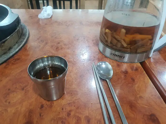 따뜻한 물이 담긴 주전자와 놋수저, 젓가락이 놓여 있는 모습