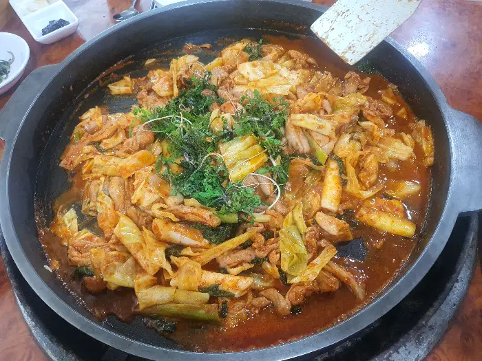 철판 위 닭갈비의 클로즈업 모습. 푸짐한 채소와 닭고기가 양념에 버무려져 있습니다.