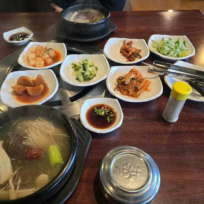 육수 가득한 뚝배기 요리와 여러 가지 반찬이 놓인 상차림