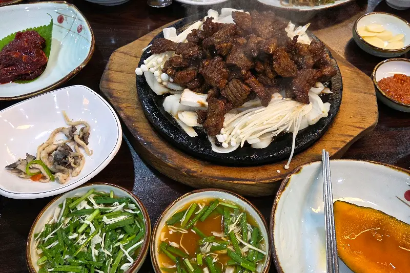 뜨거운 돌판 위의 석갈비와 다양한 밑반찬