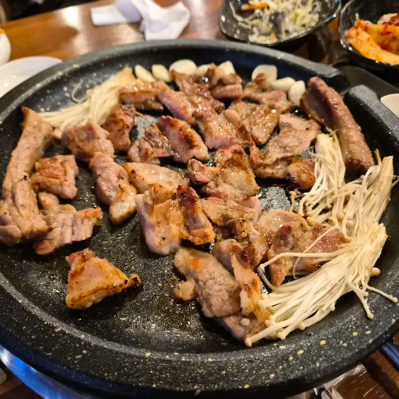 돌판 위에서 맛있게 익어가는 돼지갈비와 팽이버섯