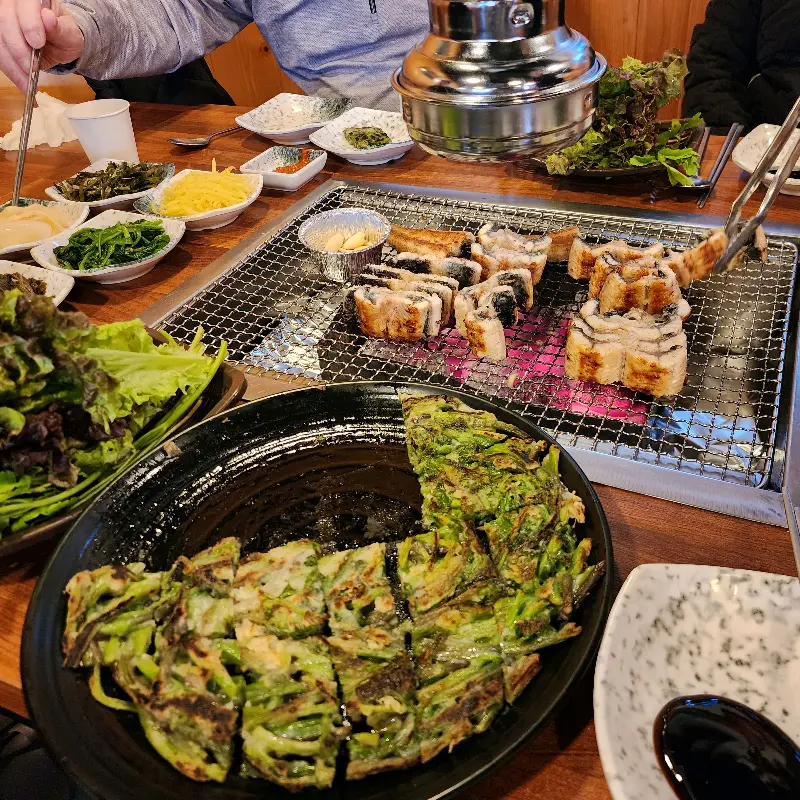 장어, 미나리전, 밑반찬이 가득한 테이블