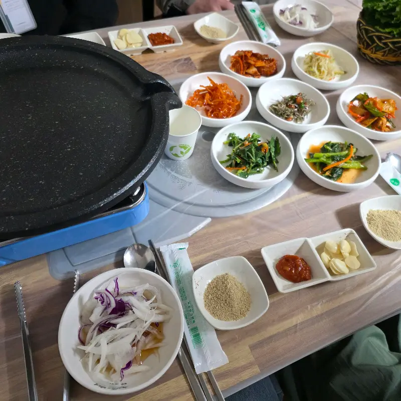 테이블 가득 차려진 밑반찬과 오리불고기