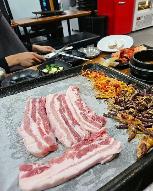 불판 위에서 맛있게 익어가는 흑돼지 삼겹살과 목살