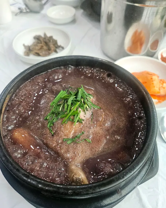 검은 뚝배기에 담겨 김이 모락모락 나는 흑미 삼계탕