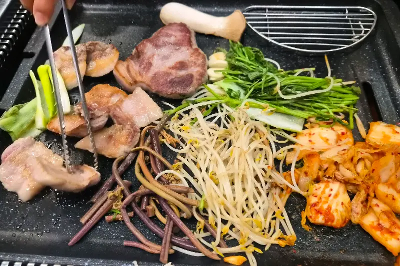 불판 위 삼겹살과 채소들