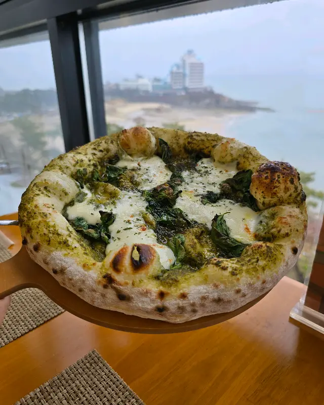 창밖으로 바다가 보이는 테이블에 놓인 피자