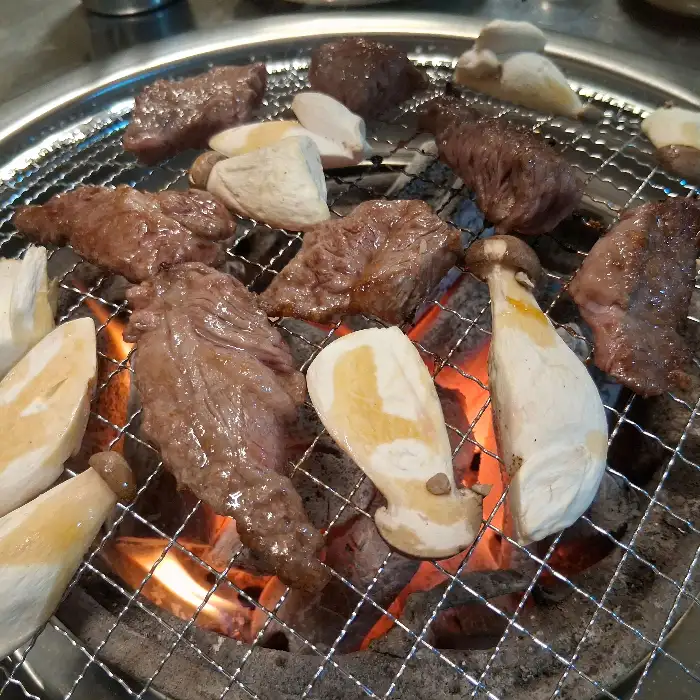 숯불 위에서 구워지는 고기와 버섯