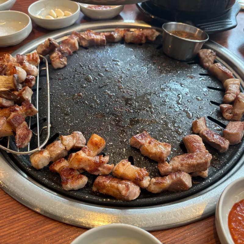 잘 구워진 삼겹살이 불판 위에 가지런히 놓여 있다.