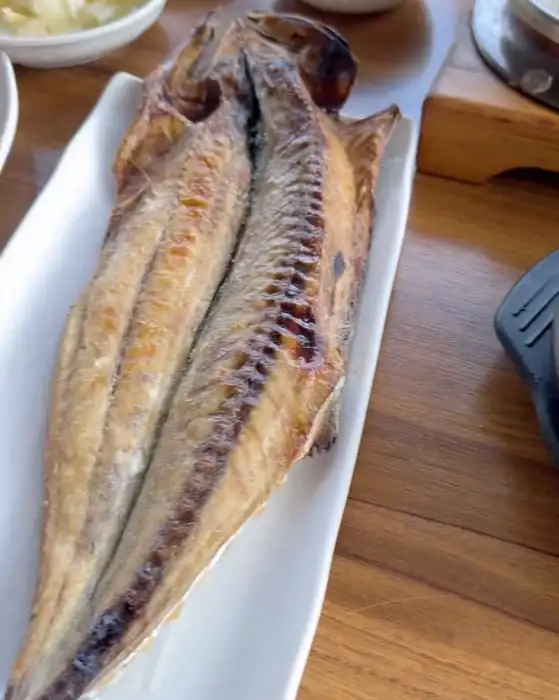 하얀 접시에 담긴 노릇하게 구워진 고등어