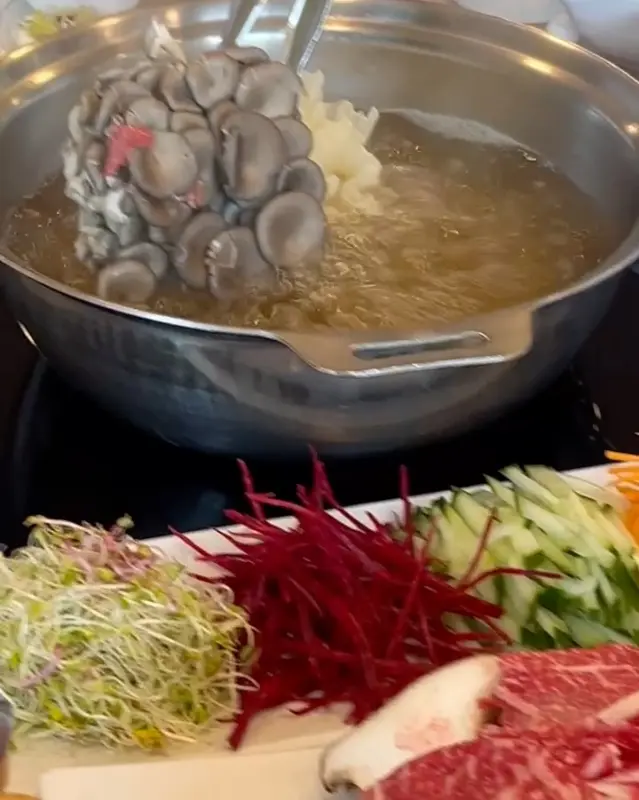 끓고 있는 샤브샤브 냄비에 버섯을 넣는 모습