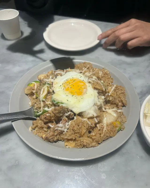 목살 필라프 위에 반숙 계란이 올려져 있는 모습