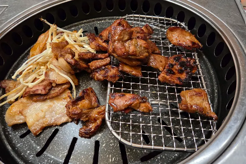 불판 위에서 맛있게 구워지고 있는 삼겹살과 목살