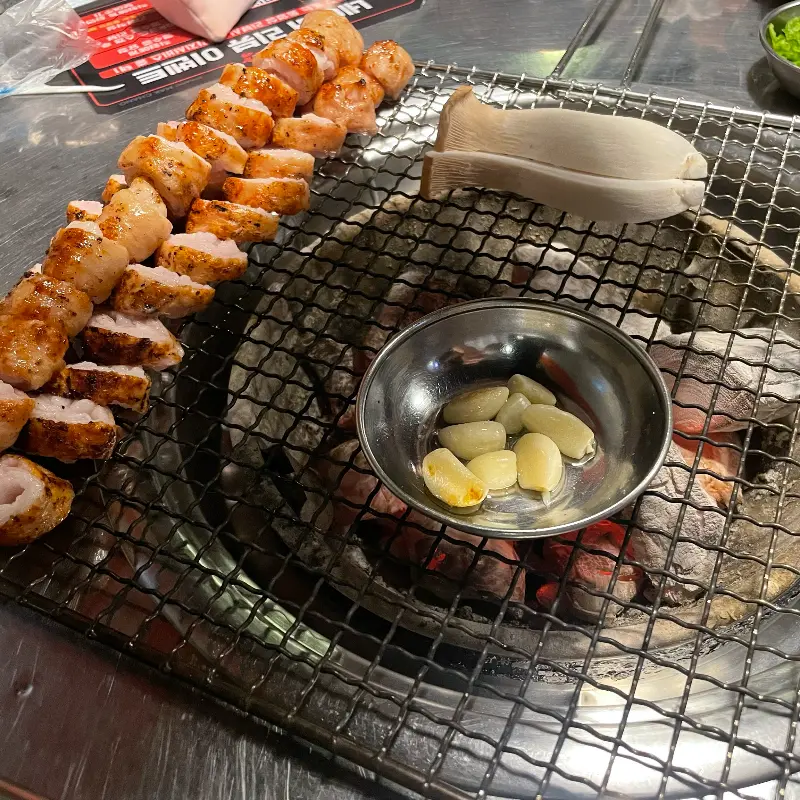 숯불 위에 올려진 막창과 버섯, 마늘
