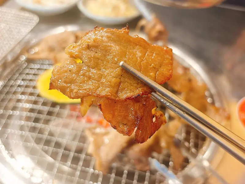 집게로 들어올린 양념갈비 한 점