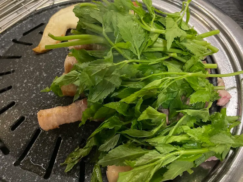 삼겹살 위에 미나리가 듬뿍 올려져 있는 모습