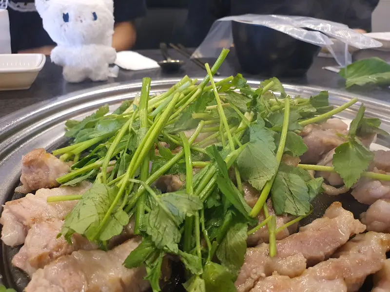 불판 위에 삼겹살과 미나리가 함께 구워지고 있는 모습