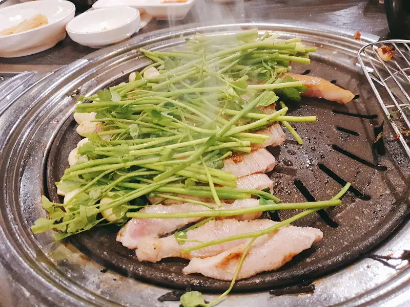 불판 위에서 구워지고 있는 삼겹살과 미나리