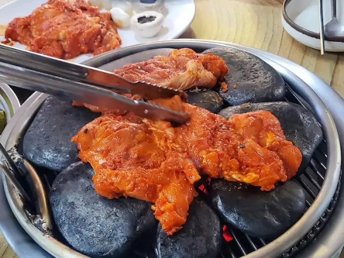 양념된 닭갈비를 집게로 뒤집는 모습