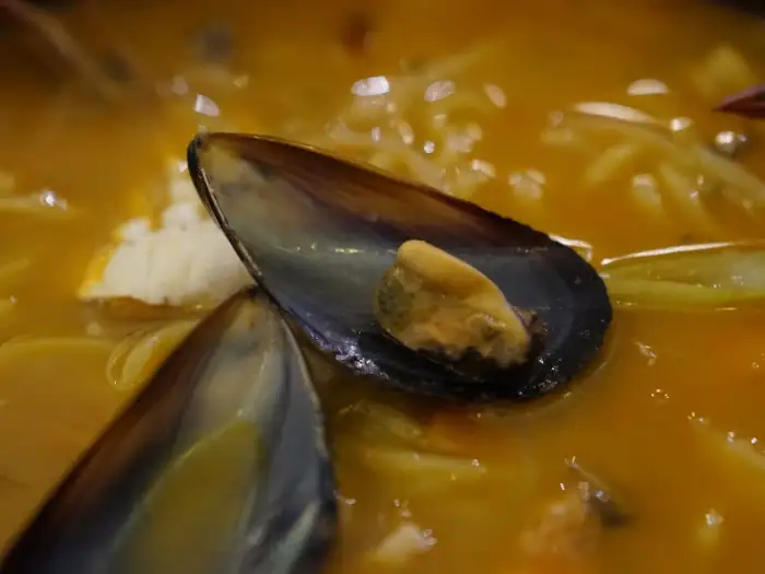 진한 노란색 국물에 홍합, 조개, 오징어 등 해산물이 가득 들어있는 짬뽕입니다. 국물 위로 떠 있는 홍합 껍데기가 먹음직스러워 보입니다.