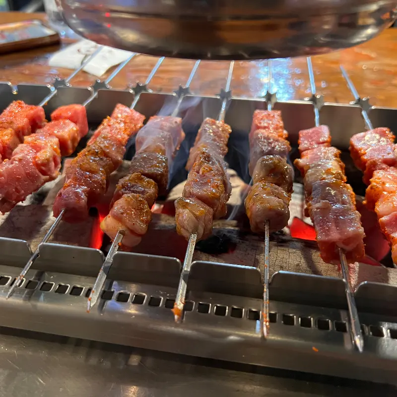 숯불 위에서 노릇노릇하게 익어가는 양꼬치의 클로즈업 샷