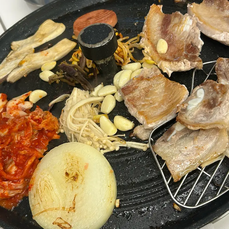 잘 익은 삼겹살과 구운 김치, 구운 양파, 구운 버섯의 조화